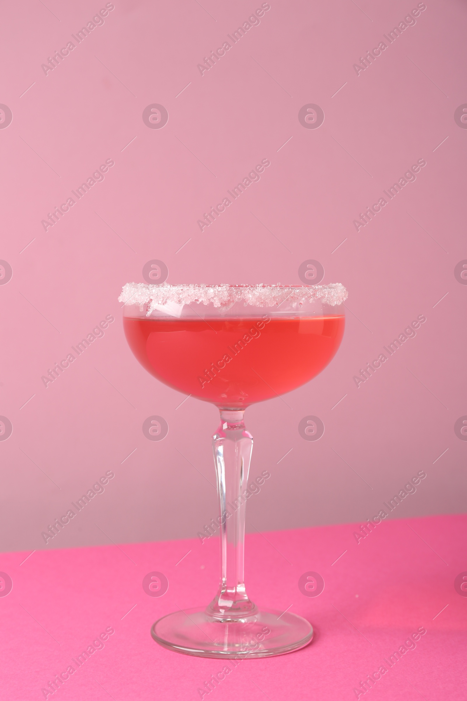 Martini cocktail with sugar in glass on pink background, closeup Photo of Martini cocktail with sugar in glass on pink background, closeup