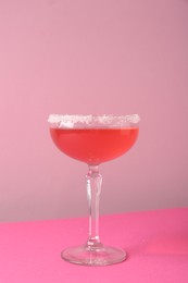 Photo of Martini cocktail with sugar in glass on pink background, closeup