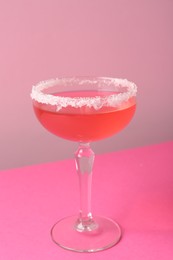 Photo of Martini cocktail with sugar in glass on pink background, closeup