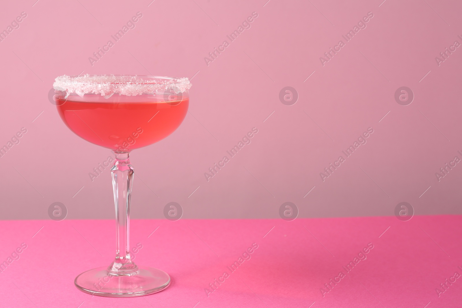 Martini cocktail with sugar in glass on pink background, closeup. Space for text Photo of Martini cocktail with sugar in glass on pink background, closeup. Space for text