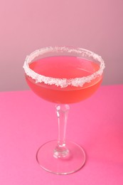 Photo of Martini cocktail with sugar in glass on pink background, closeup