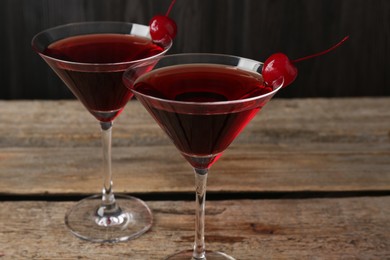 Photo of Martini cocktail with cherries in glasses on wooden table, closeup
