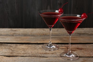 Photo of Martini cocktail with cherries in glasses on wooden table, closeup. Space for text