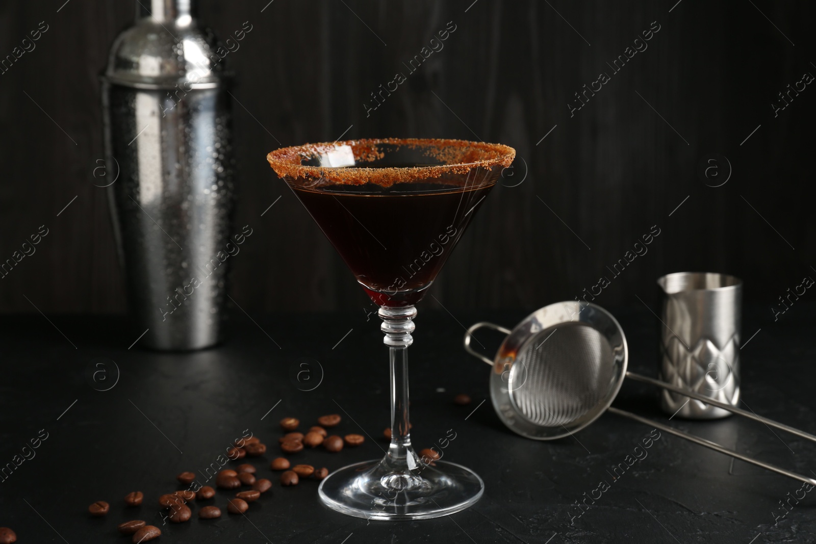 Martini cocktail with sugar in glass, coffee beans and shaker on black table, closeup Photo of Martini cocktail with sugar in glass, coffee beans and shaker on black table, closeup