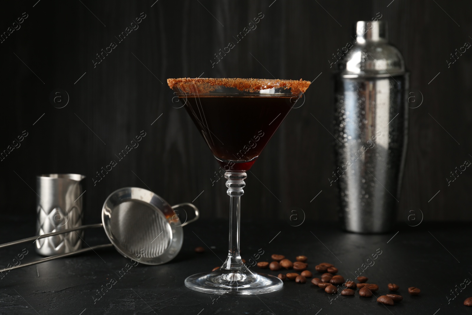 Martini cocktail with sugar in glass, coffee beans and shaker on black table, closeup Photo of Martini cocktail with sugar in glass, coffee beans and shaker on black table, closeup