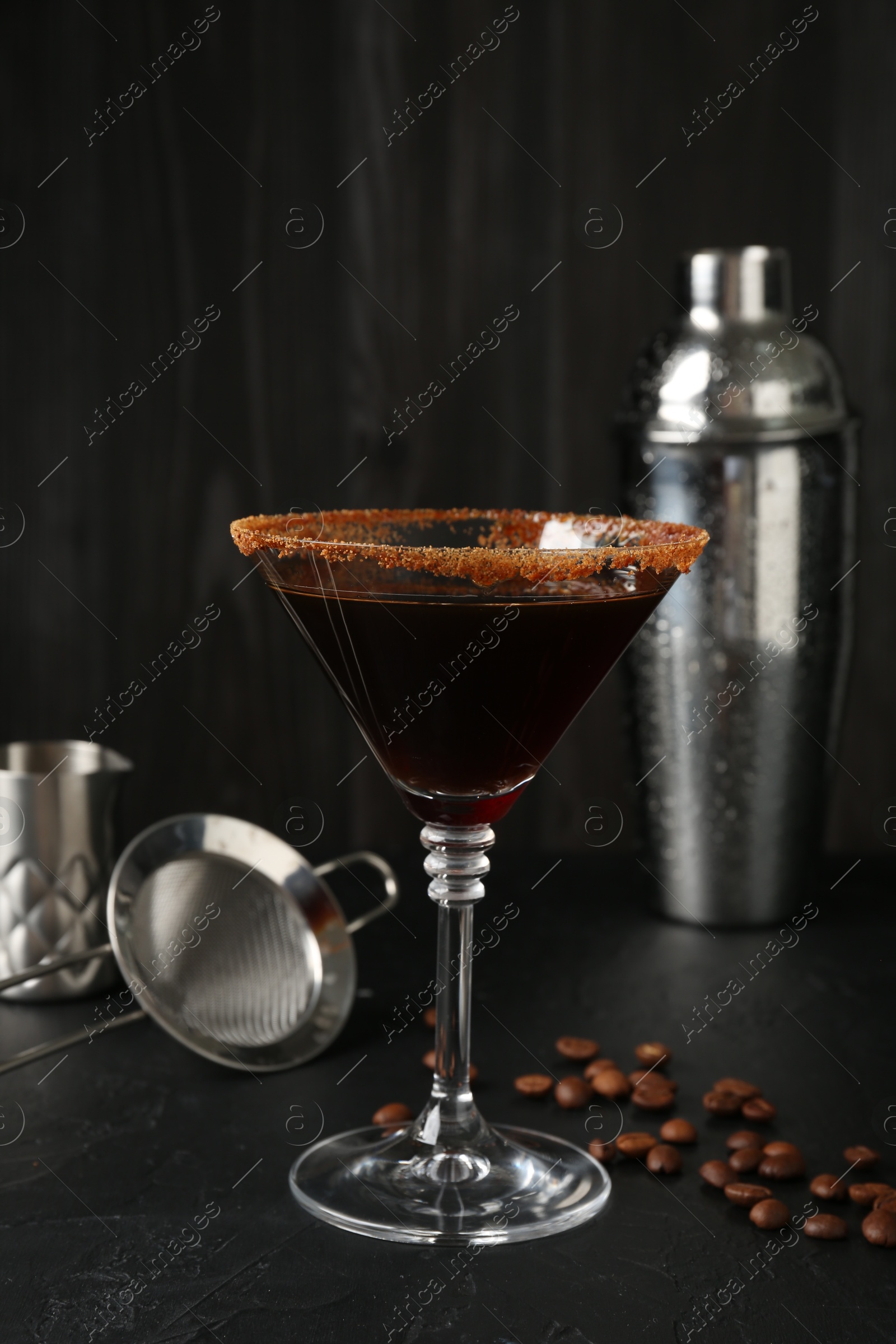 Martini cocktail with sugar in glass, coffee beans and shaker on black table, closeup Photo of Martini cocktail with sugar in glass, coffee beans and shaker on black table, closeup