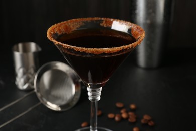 Photo of Martini cocktail with sugar in glass and coffee beans on black table, closeup