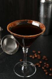 Photo of Martini cocktail with sugar in glass and coffee beans on black table, closeup
