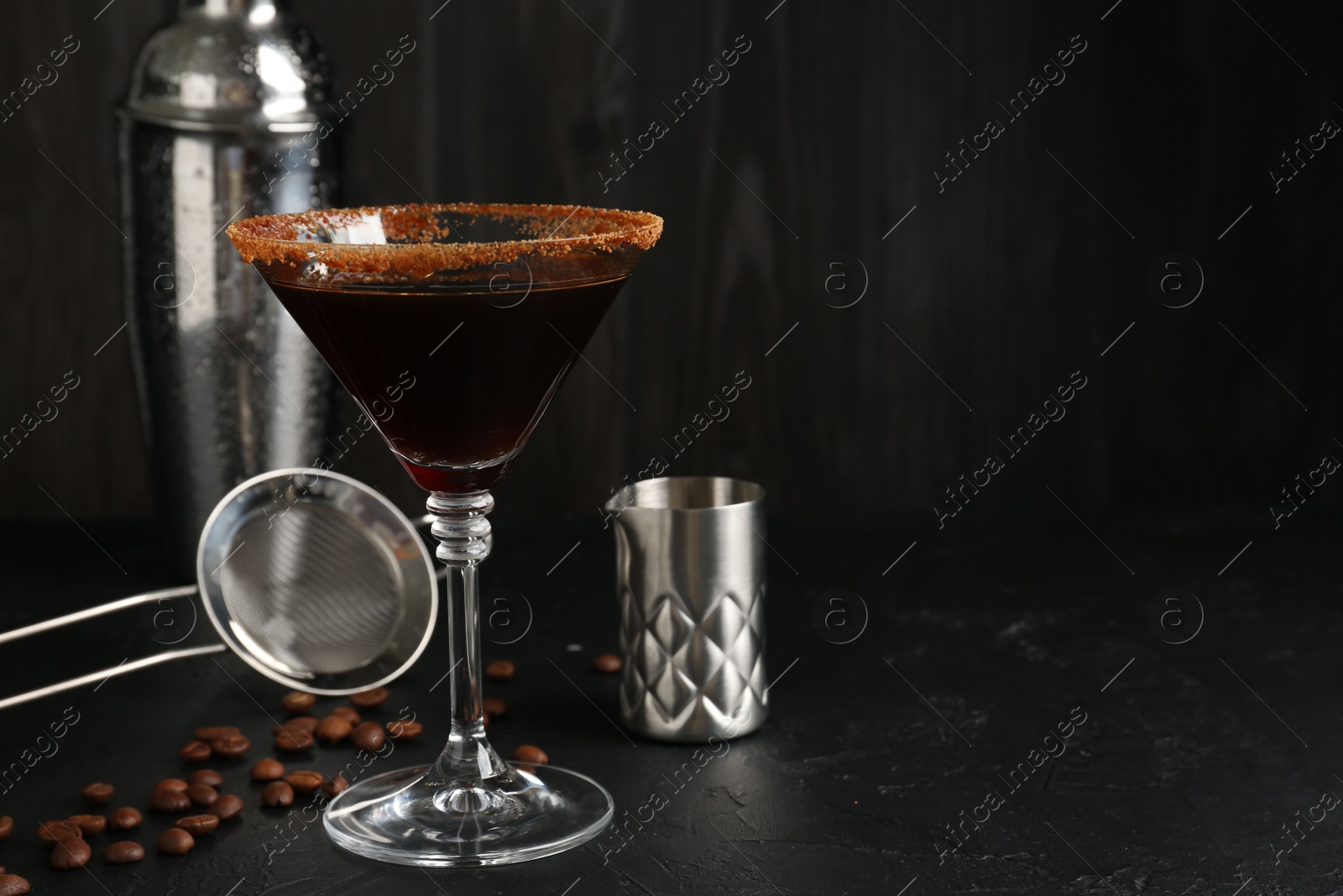 Martini cocktail with sugar in glass, coffee beans and shaker on black table, closeup. Space for text Photo of Martini cocktail with sugar in glass, coffee beans and shaker on black table, closeup. Space for text