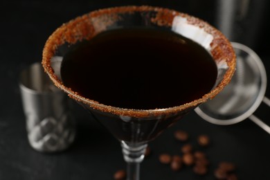 Photo of Martini cocktail with sugar in glass and coffee beans on black table, closeup