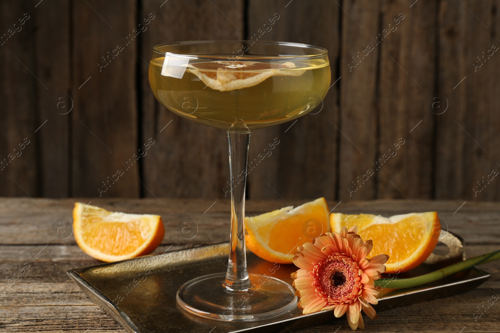 Martini cocktail in glass, orange slices and flower on wooden table, closeup Photo of Martini cocktail in glass, orange slices and flower on wooden table, closeup