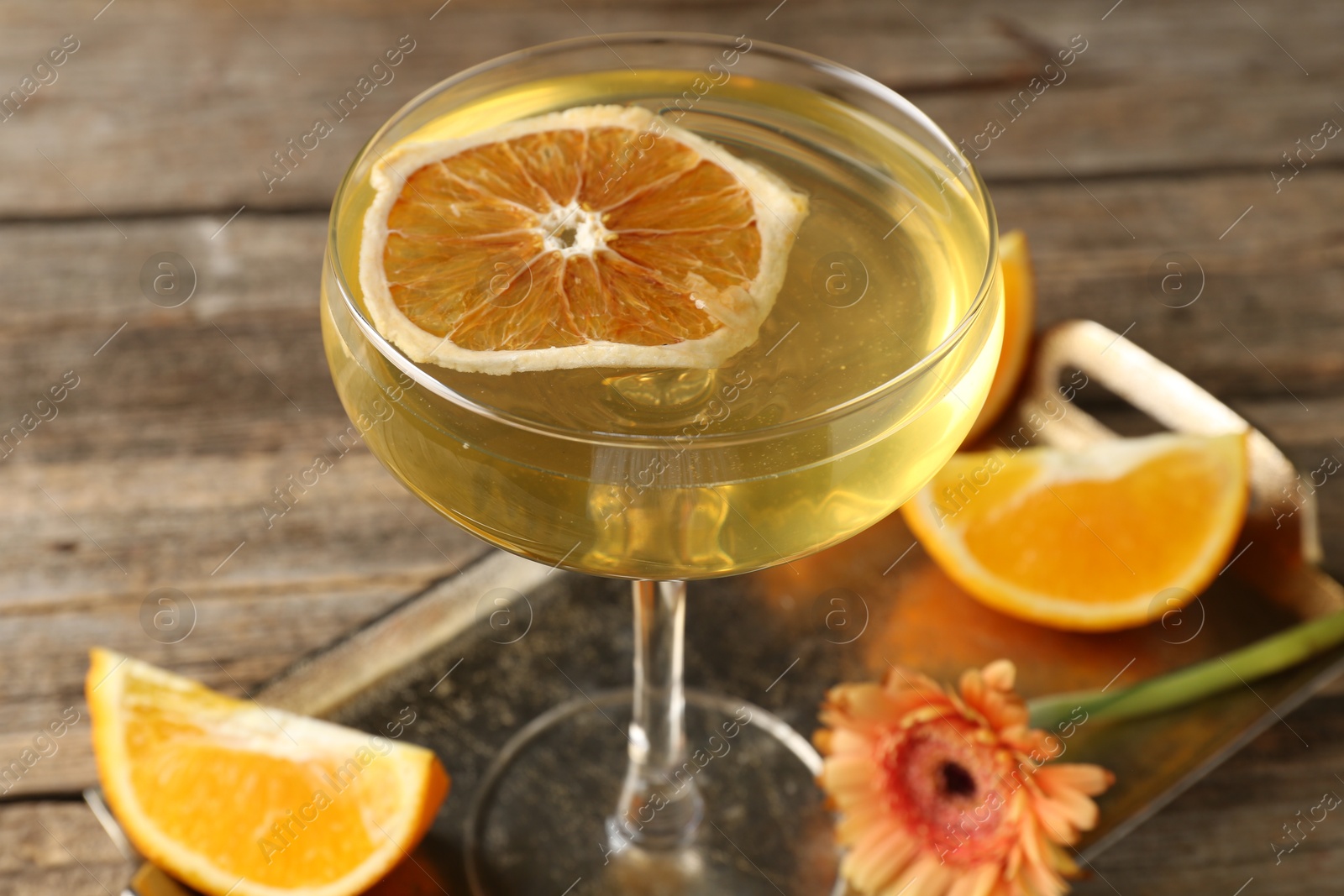 Martini cocktail in glass, orange slices and flower on wooden table, closeup Photo of Martini cocktail in glass, orange slices and flower on wooden table, closeup