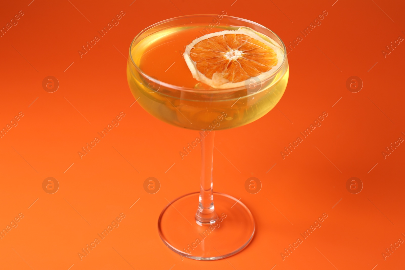Martini cocktail with orange slice in glass on orange background, closeup Photo of Martini cocktail with orange slice in glass on orange background, closeup