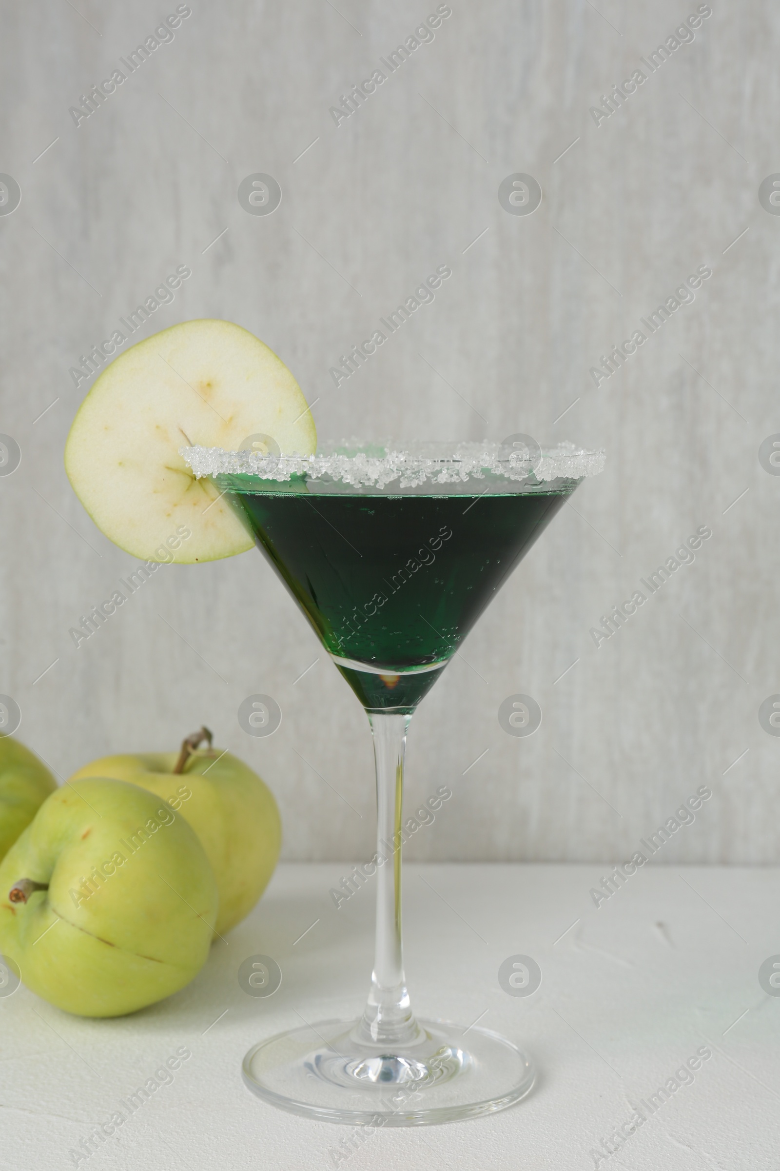 Martini cocktail with apple slice in glass and fruits on white table, closeup Photo of Martini cocktail with apple slice in glass and fruits on white table, closeup