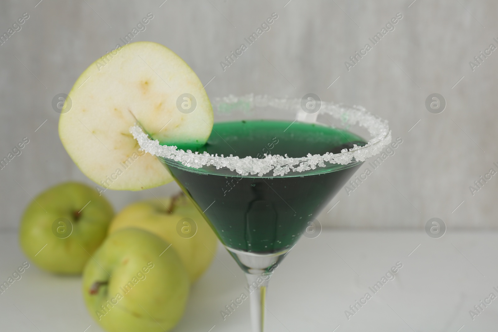 Martini cocktail with apple slice in glass and fruits on white table, closeup Photo of Martini cocktail with apple slice in glass and fruits on white table, closeup