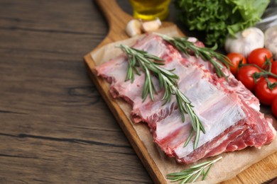 Photo of Fresh raw beef ribs and ingredients on wooden table, closeup. Space for text