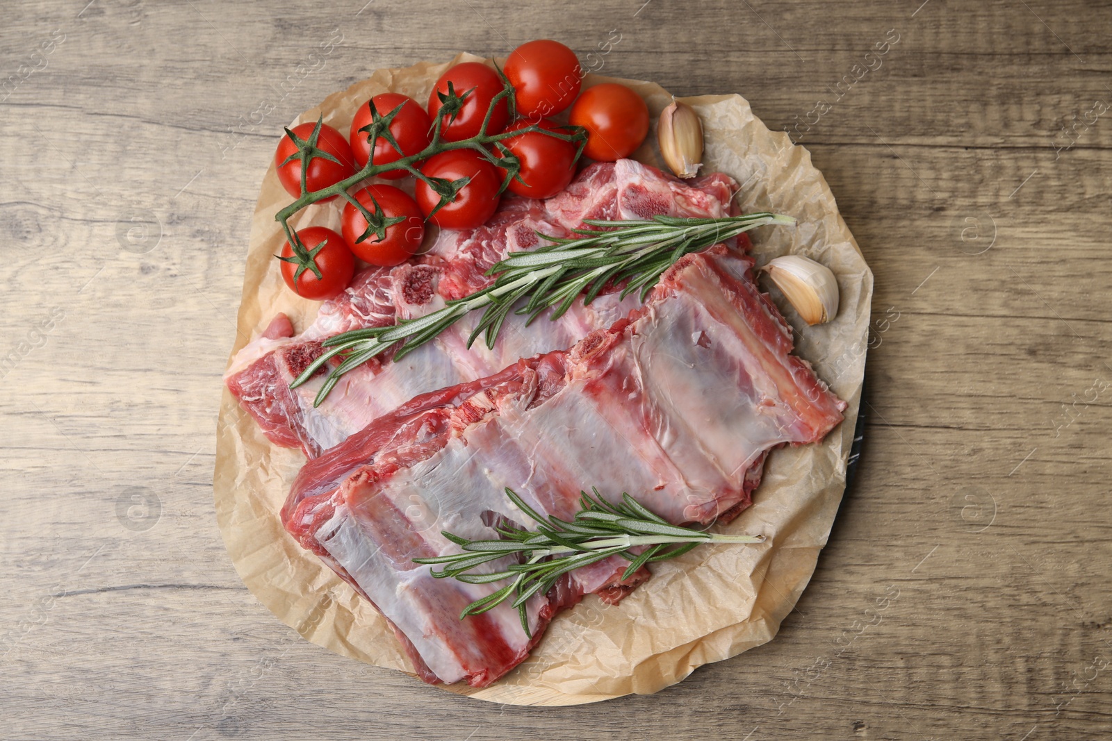 Photo of Fresh raw beef ribs, tomatoes and spices on wooden table, top view