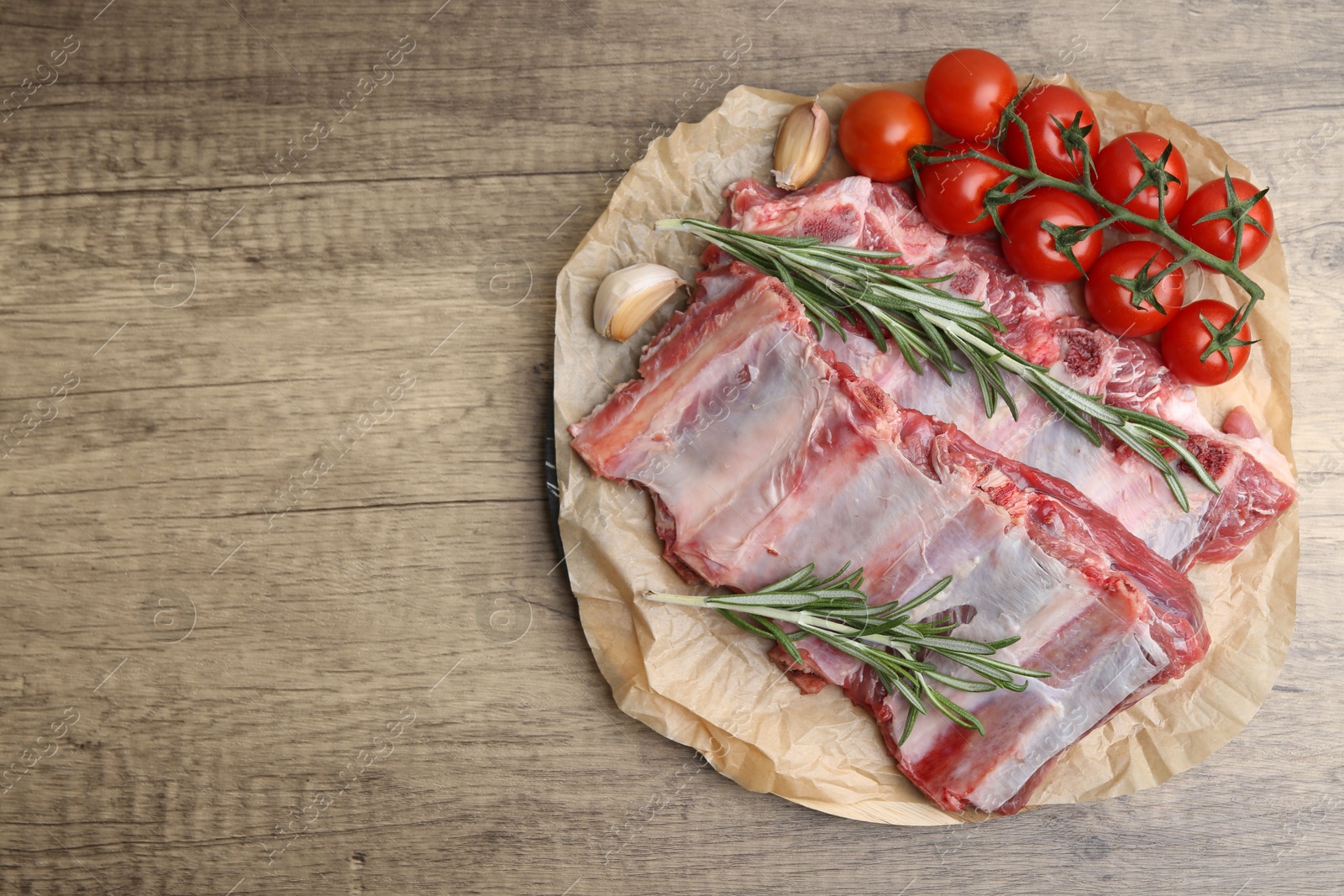 Photo of Fresh raw beef ribs, tomatoes and spices on wooden table, top view. Space for text