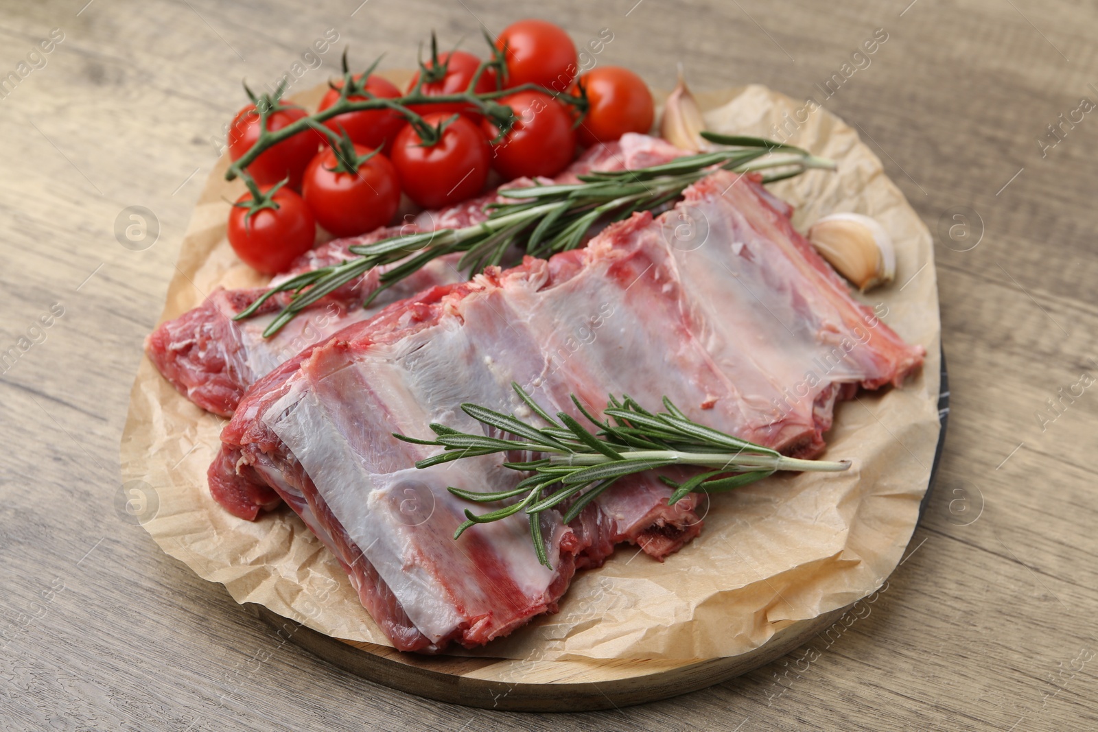 Photo of Fresh raw beef ribs, tomatoes and spices on wooden table, closeup