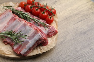 Photo of Fresh raw beef ribs, tomatoes and spices on wooden table, closeup. Space for text