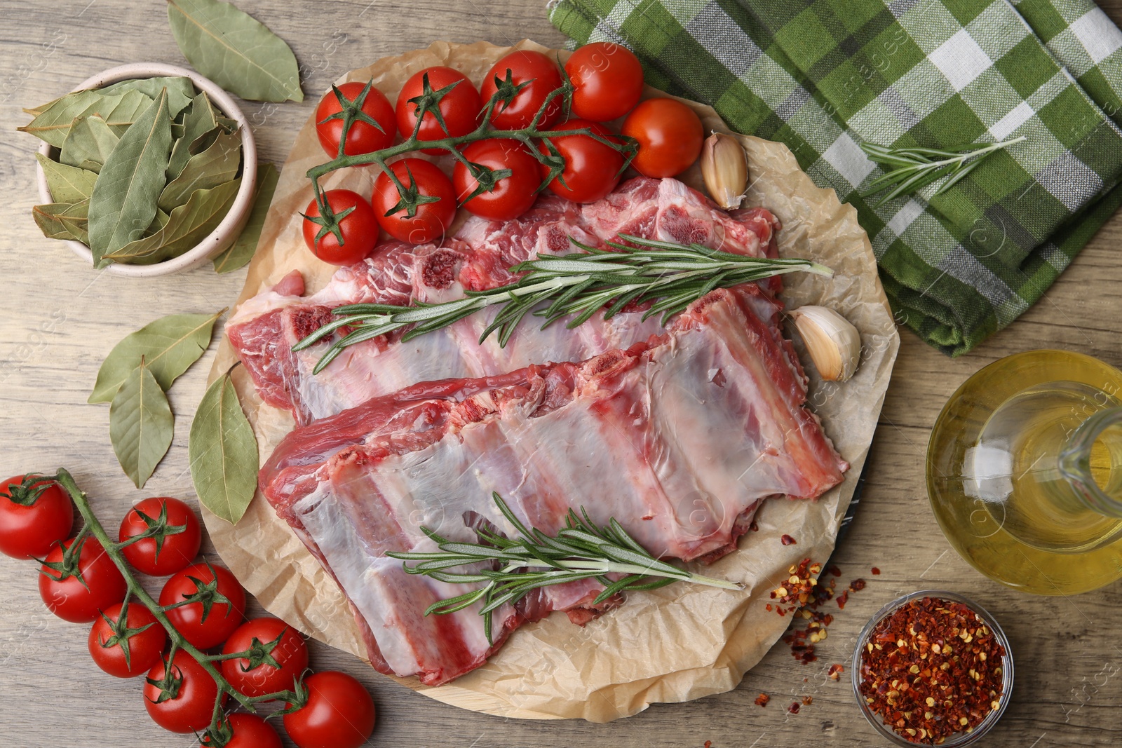Fresh raw beef ribs, tomatoes and spices on wooden table, flat lay Photo of Fresh raw beef ribs, tomatoes and spices on wooden table, flat lay