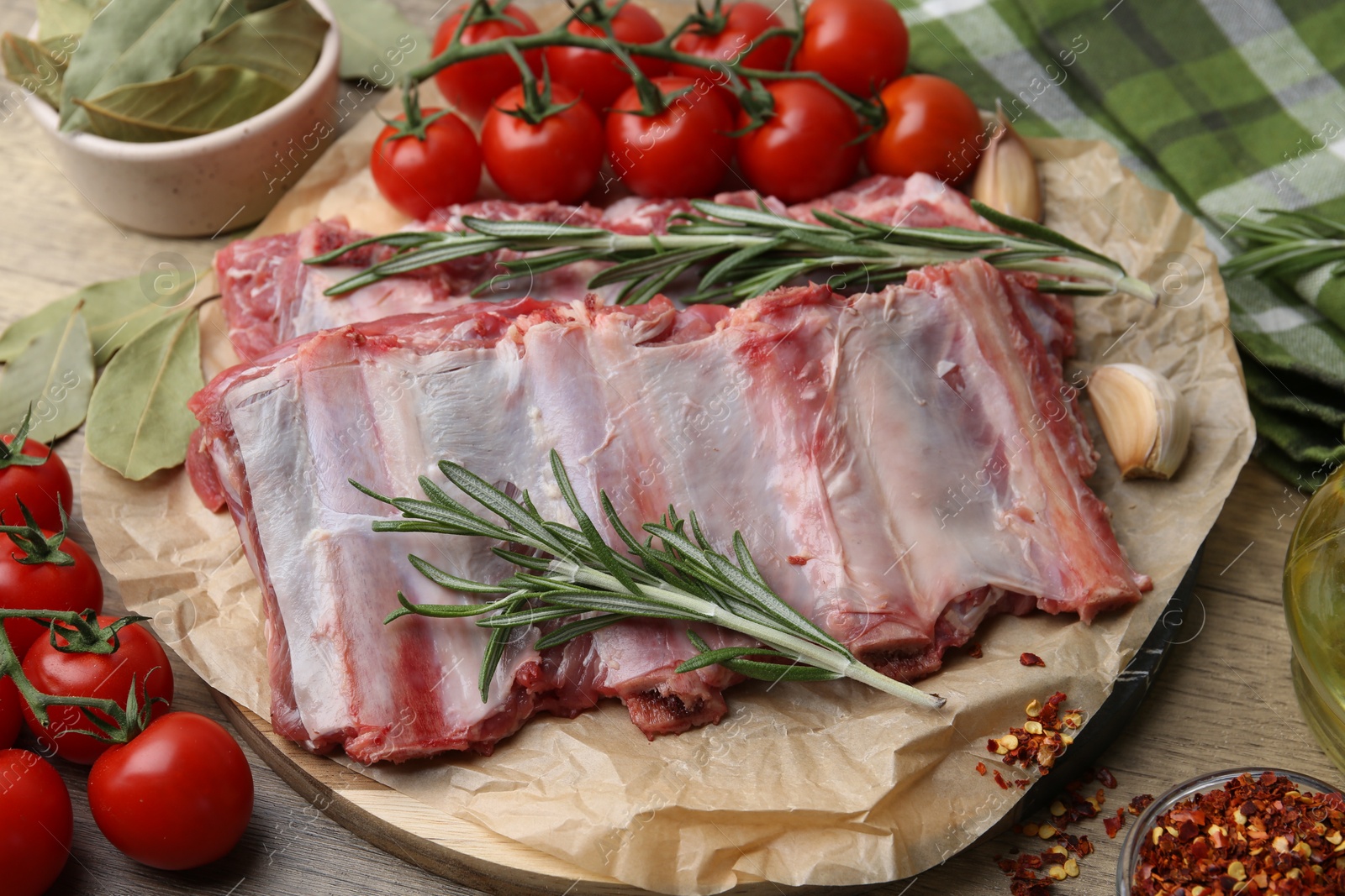 Fresh raw beef ribs, tomatoes and spices on wooden table, closeup Photo of Fresh raw beef ribs, tomatoes and spices on wooden table, closeup