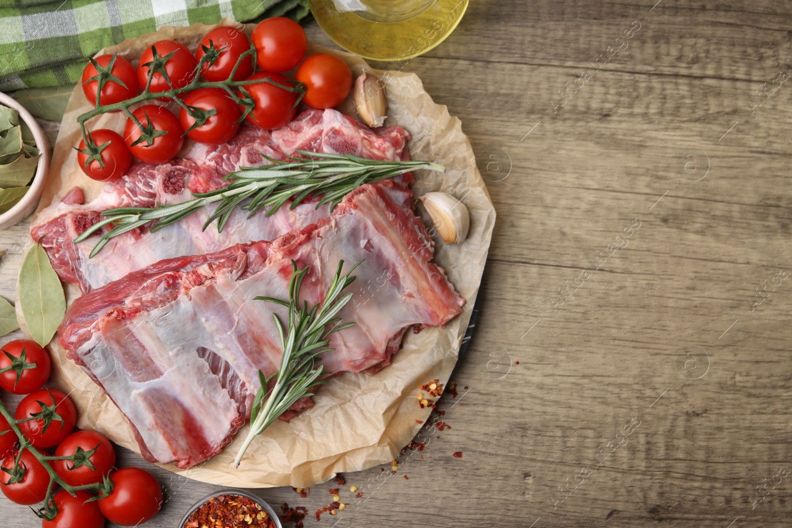 Fresh raw beef ribs, tomatoes and spices on wooden table, flat lay. Space for text Photo of Fresh raw beef ribs, tomatoes and spices on wooden table, flat lay. Space for text
