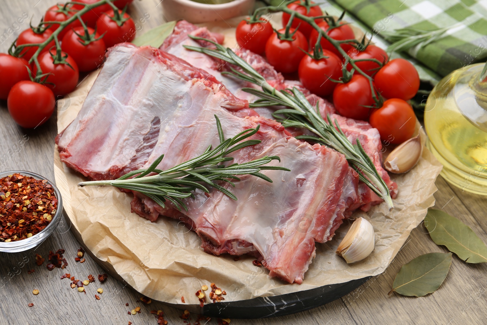 Fresh raw beef ribs, tomatoes and spices on wooden table, closeup Photo of Fresh raw beef ribs, tomatoes and spices on wooden table, closeup
