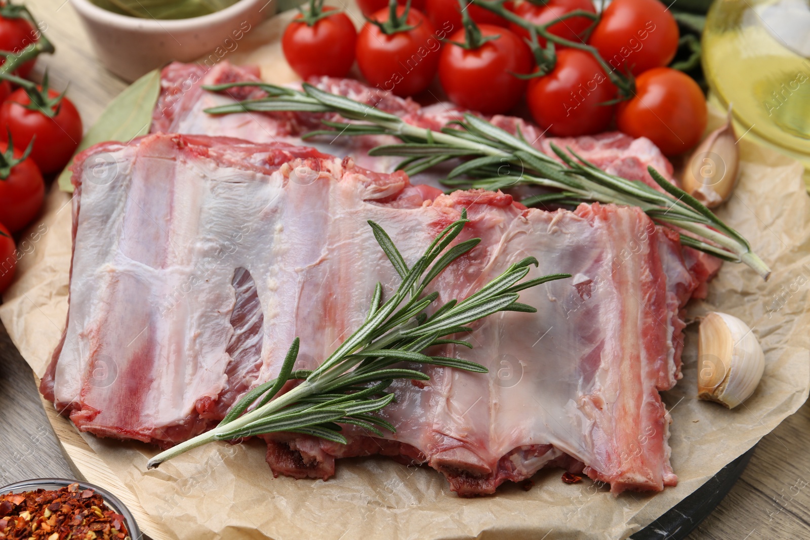 Fresh raw beef ribs, tomatoes and spices on wooden table, closeup Photo of Fresh raw beef ribs, tomatoes and spices on wooden table, closeup