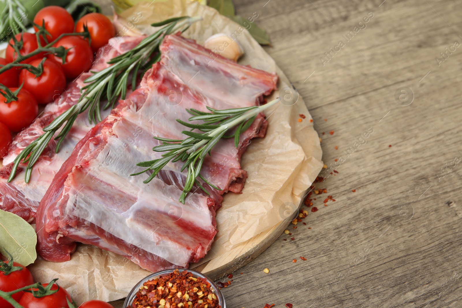 Fresh raw beef ribs, tomatoes and spices on wooden table, closeup. Space for text Photo of Fresh raw beef ribs, tomatoes and spices on wooden table, closeup. Space for text