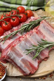 Photo of Fresh raw beef ribs, tomatoes and spices on table, closeup