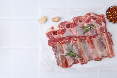 Photo of Fresh raw beef ribs and spices on white tiled table, flat lay. Space for text