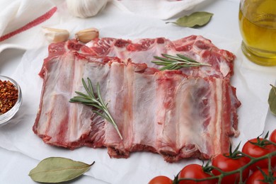 Photo of Fresh raw beef ribs, tomatoes and spices on table, above view