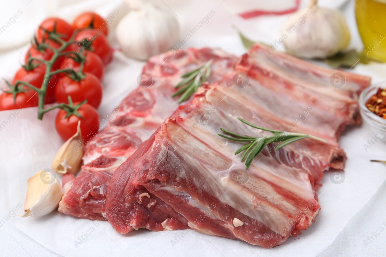Photo of Fresh raw beef ribs, tomatoes and spices on table, closeup