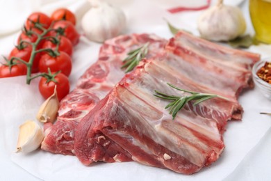 Photo of Fresh raw beef ribs, tomatoes and spices on table, closeup