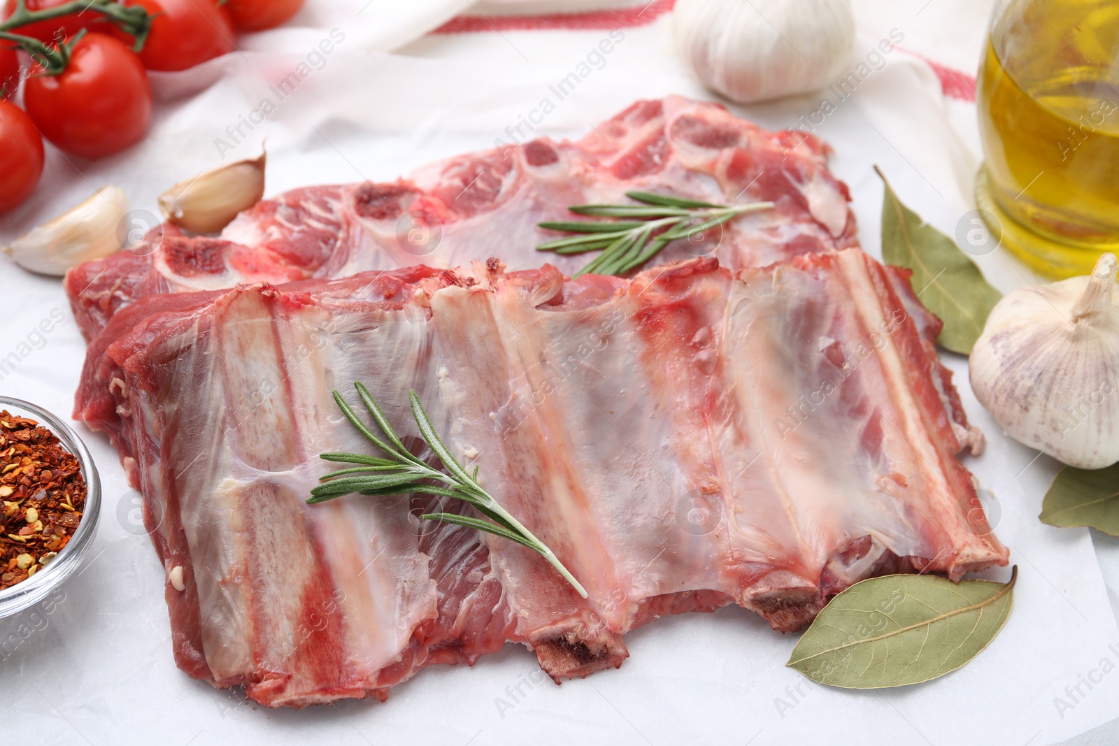 Photo of Fresh raw beef ribs, tomatoes and spices on table, closeup