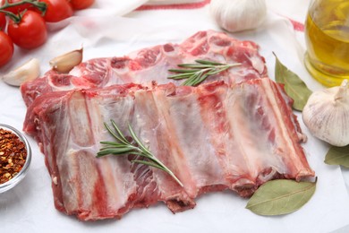 Photo of Fresh raw beef ribs, tomatoes and spices on table, closeup