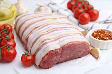 Photo of Piece of raw beef meat, tomatoes and spices on table, closeup