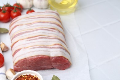 Photo of Piece of raw beef meat, tomatoes and spices on white tiled table, closeup. Space for text