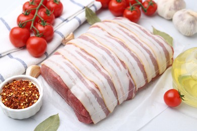 Photo of Piece of raw beef meat, tomatoes and spices on white table, closeup