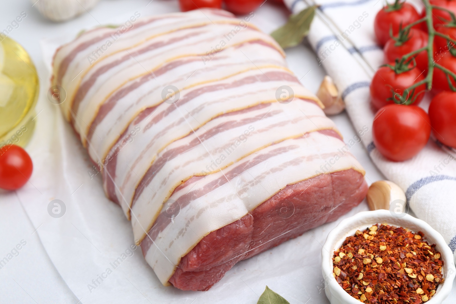 Piece of raw beef meat, tomatoes and spices on white table, closeup Photo of Piece of raw beef meat, tomatoes and spices on white table, closeup