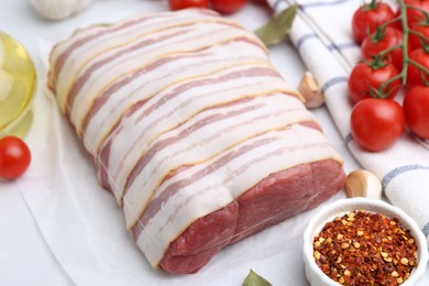 Photo of Piece of raw beef meat, tomatoes and spices on white table, closeup