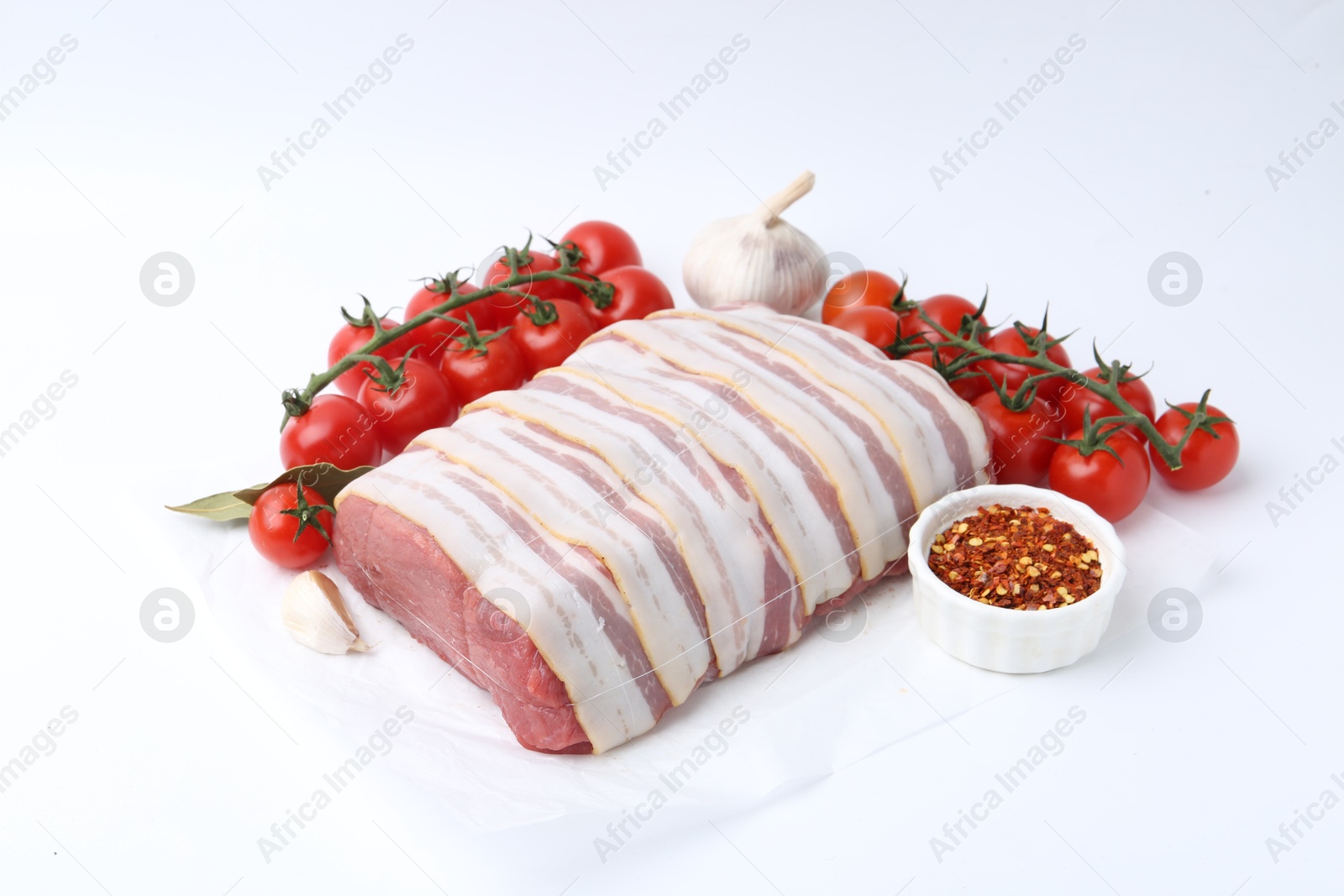 Piece of raw beef meat, tomatoes and spices on white background Photo of Piece of raw beef meat, tomatoes and spices on white background