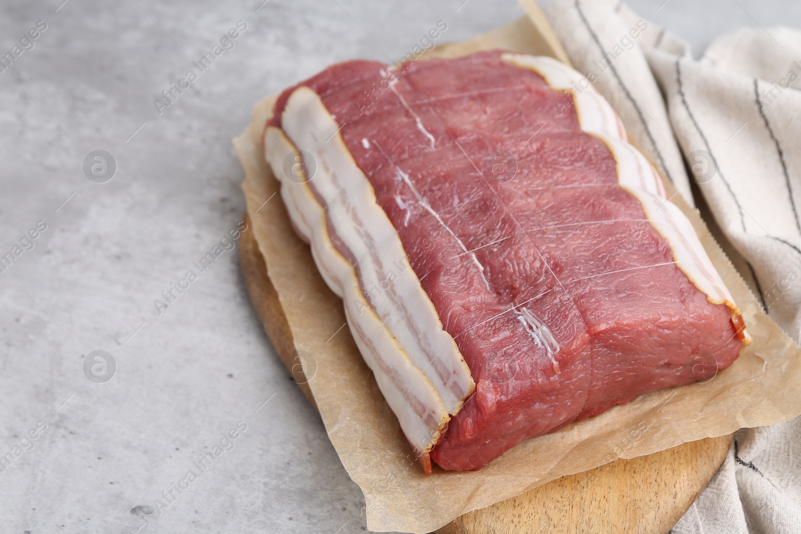 Photo of Piece of raw beef meat on grey table, closeup. Space for text
