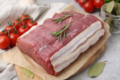 Photo of Piece of raw beef meat, tomatoes and spices on grey table, closeup
