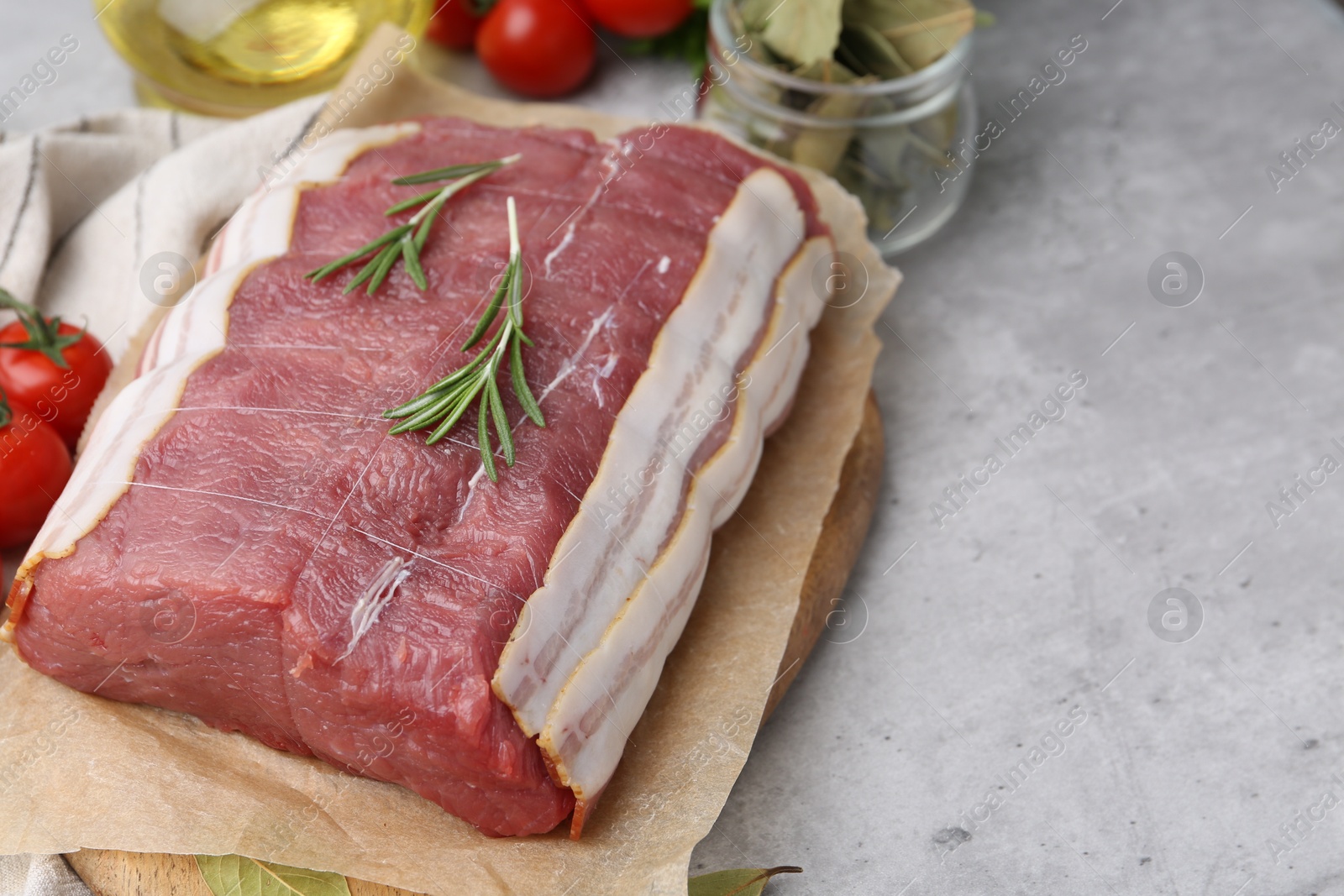 Piece of raw beef meat, tomatoes and spices on grey table, closeup. Space for text Photo of Piece of raw beef meat, tomatoes and spices on grey table, closeup. Space for text