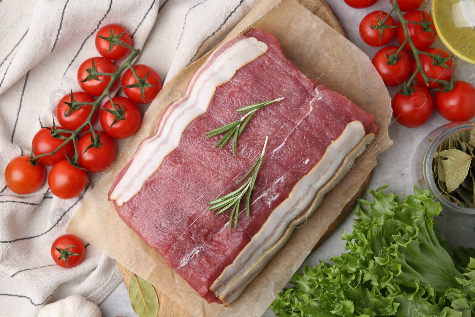 Piece of raw beef meat, tomatoes and spices on grey table, flat lay Photo of Piece of raw beef meat, tomatoes and spices on grey table, flat lay