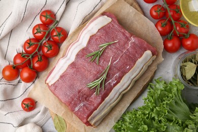 Photo of Piece of raw beef meat, tomatoes and spices on grey table, flat lay