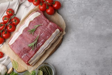 Photo of Piece of raw beef meat, tomatoes and spices on grey table, flat lay. Space for text