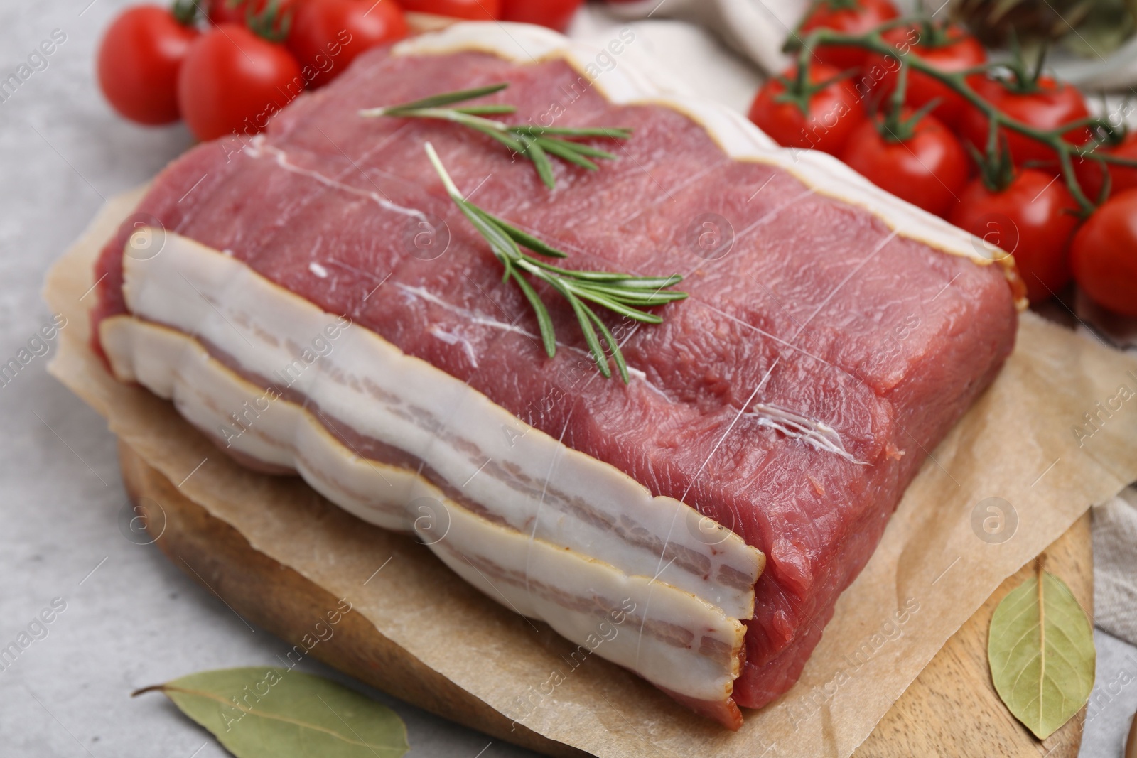 Piece of raw beef meat, tomatoes and spices on grey table, closeup Photo of Piece of raw beef meat, tomatoes and spices on grey table, closeup
